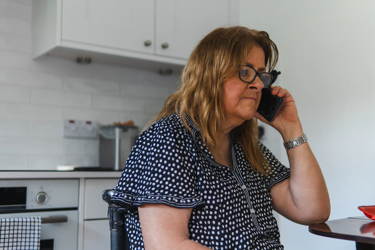 Femme au téléphone dans sa cuisine, prévenue par la plateforme de téléassistance