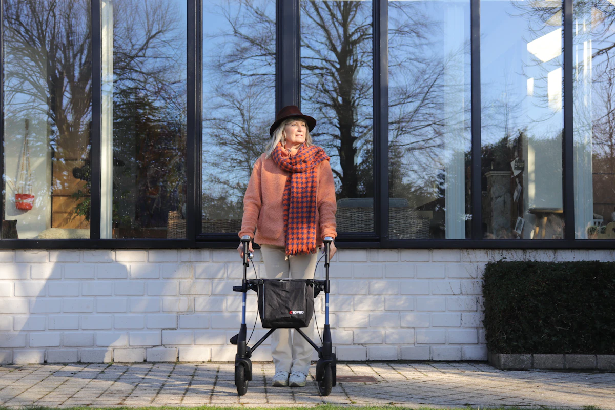 Femme âgée avec un déambulateur devant de grandes fenêtres