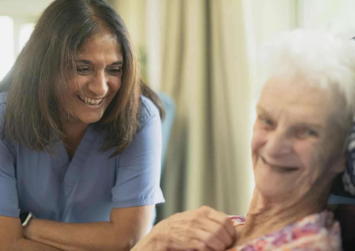 Infirmière souriante auprès d’un patient âgé