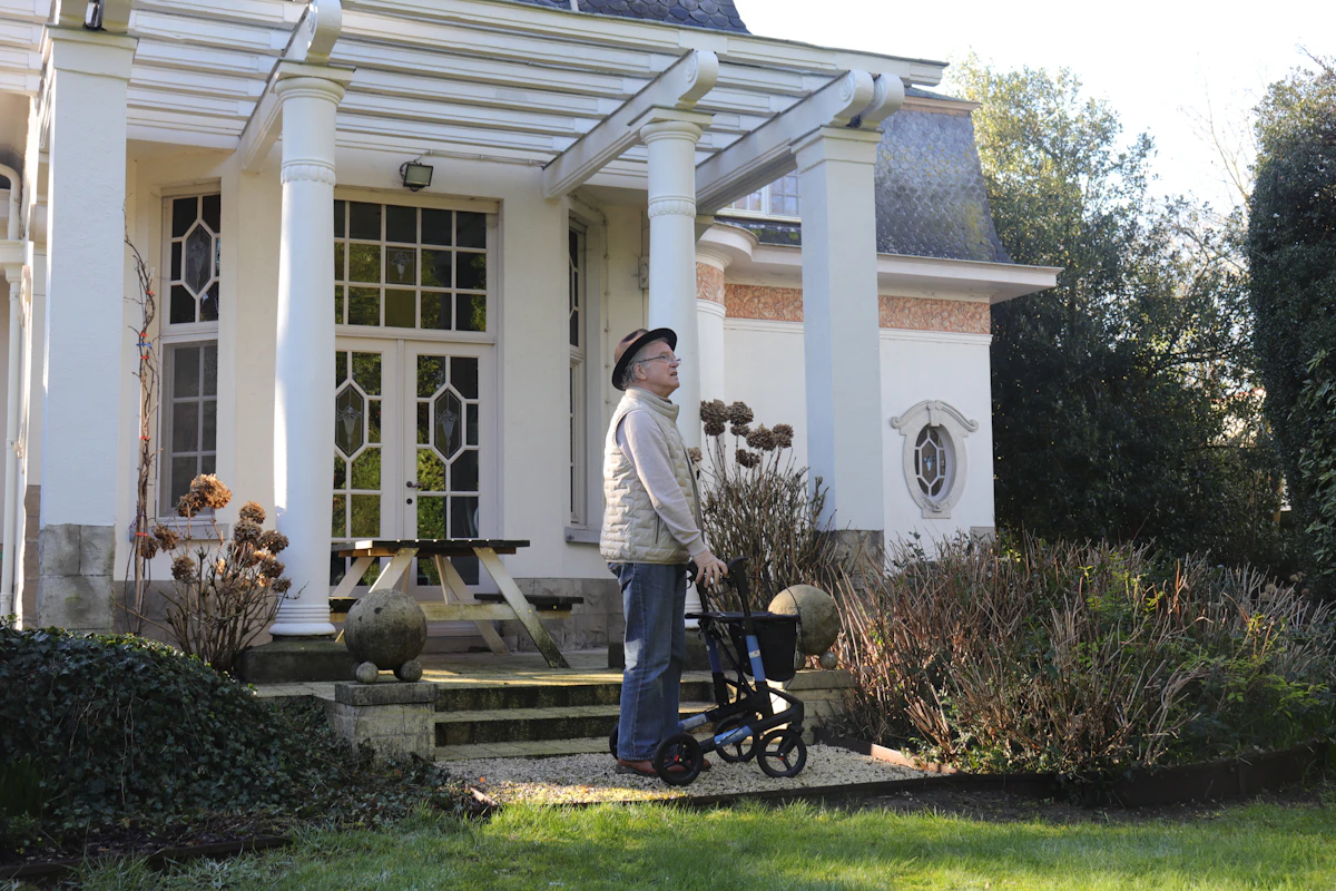 Senior avec un déambulateur devant les marches de sa maison
