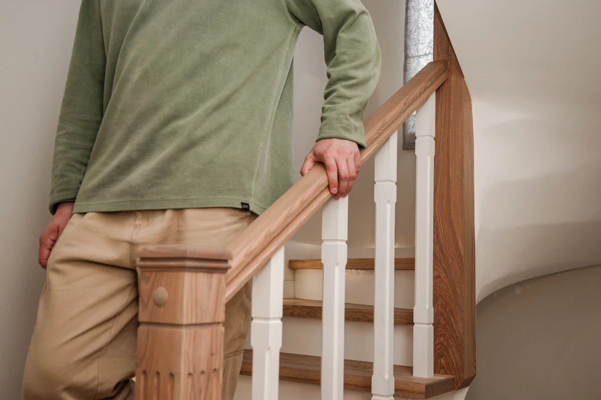 Personne âgée descendant l’escalier de sa maison en tenant la rampe